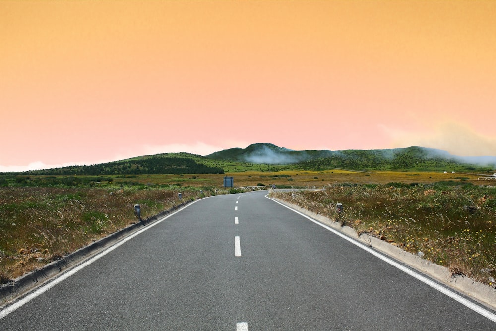 carretera de hormigón gris bajo el cielo nublado naranja durante el día