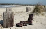 Short surf boots without finger covers displayed on sandy beach.