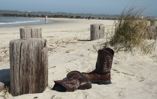 Short surf boots without finger covers displayed on sandy beach.