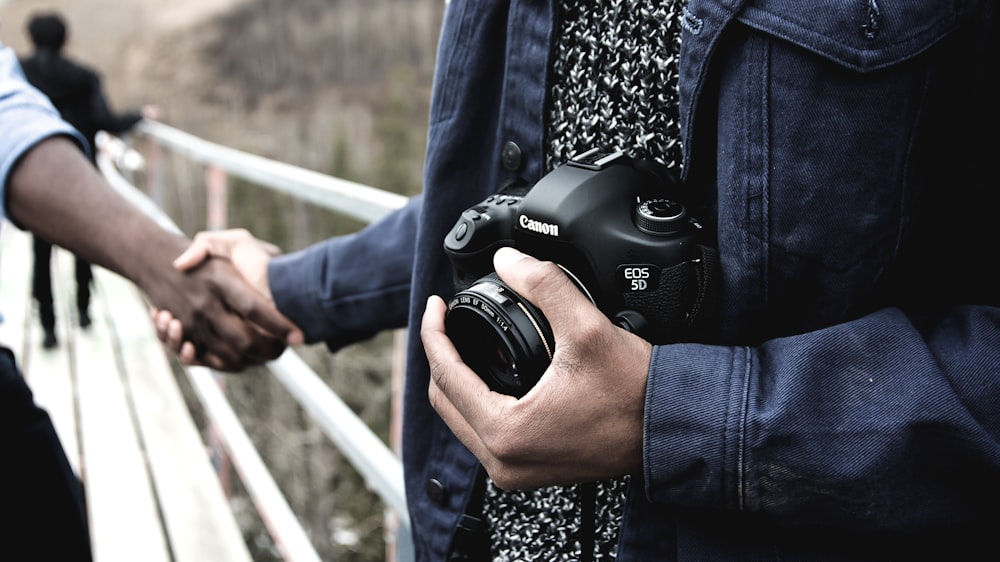 person holding Canon DSLR camera