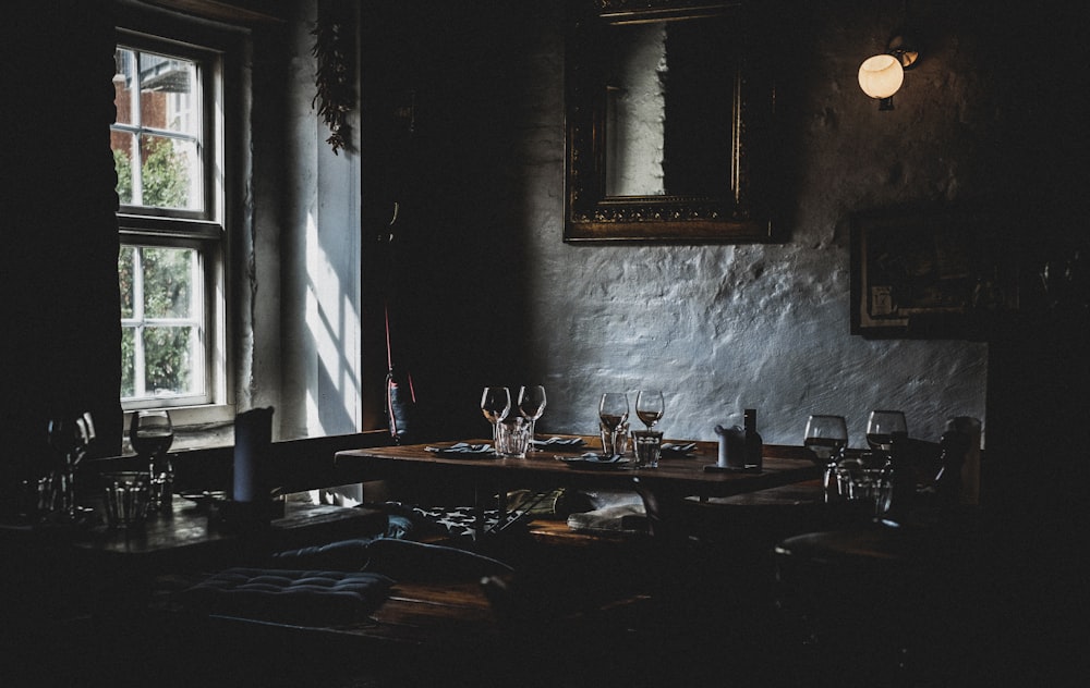 wine glasses on top of brown table near window