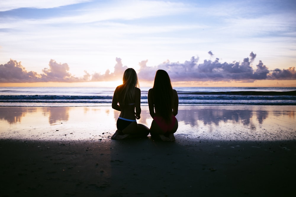 silhouette of two women facing body of water