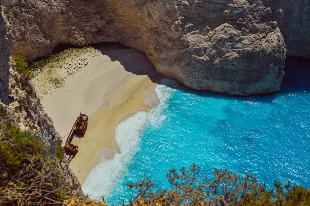 wrecked ship on shore near cliff during daytime