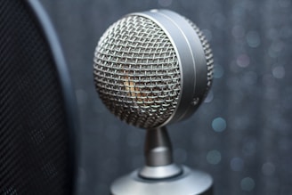 Close-up of a silver microphone with a blurred smoky jazz club background.