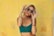 woman in blue bralette holding sunglasses putting on her eyes