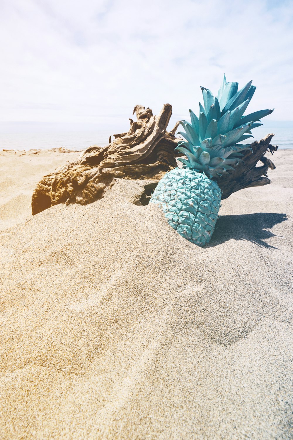 um abacaxi azul sentado em cima de uma praia de areia