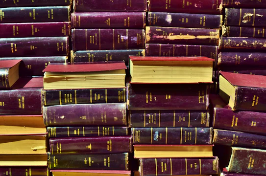 A stack of hardcover academic books with gold embossed titles on a parchment background.