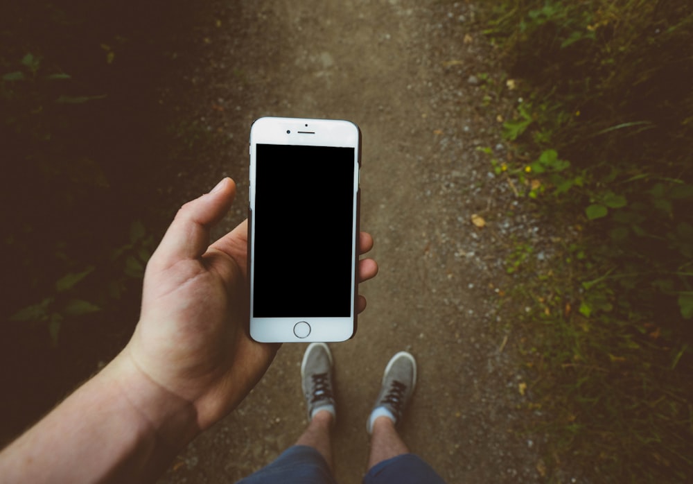 personne tenant un iPhone 6 argenté avec une coque noire