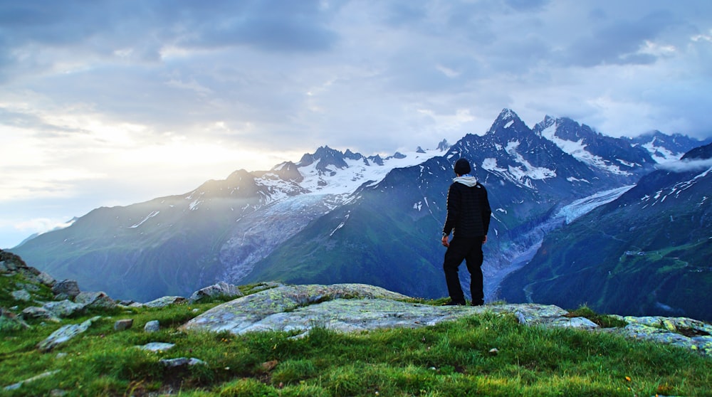 pessoa em pé na frente da fotografia da paisagem da montanha