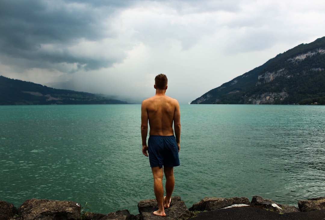 man wearing black shorts standing in front of body of water