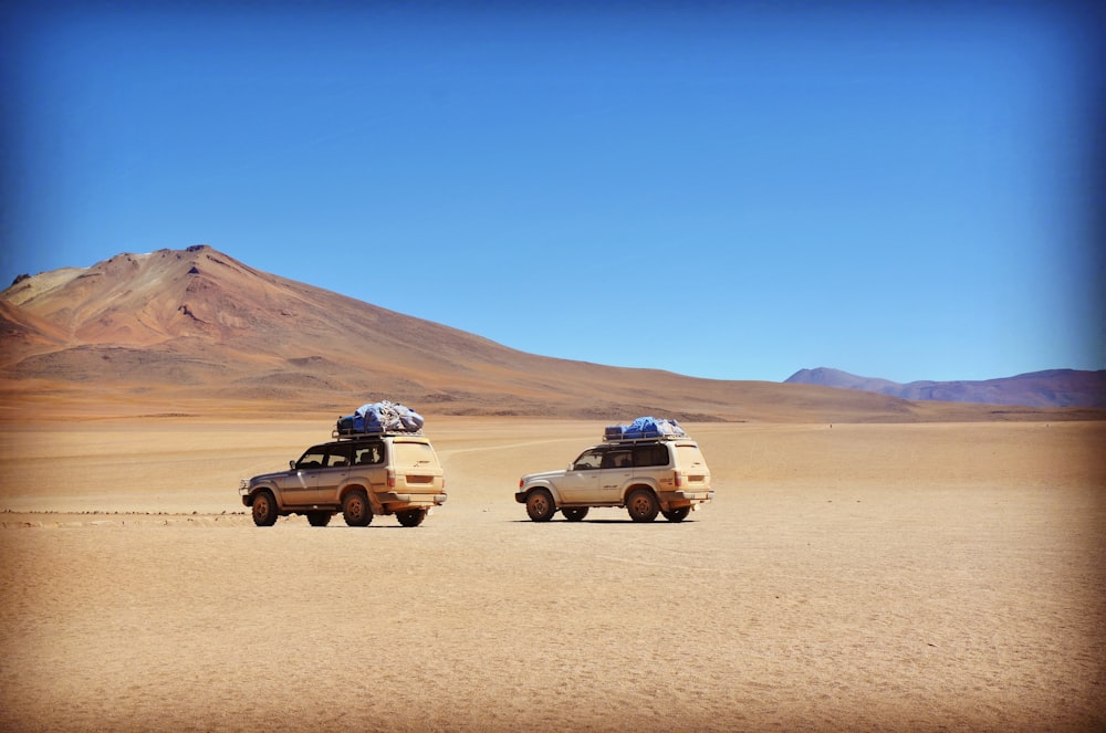dois SUVs cinzas no deserto cinza