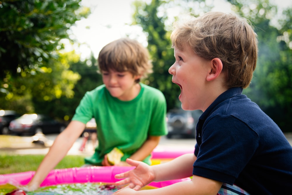 boy in blue shirt screaming near boy in green crew-neck shirt