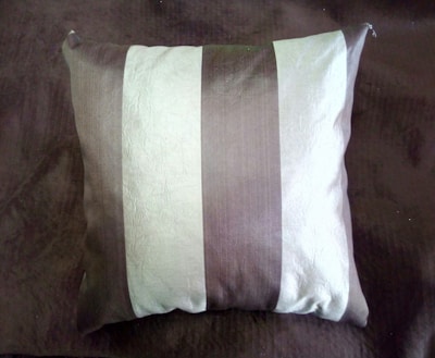 A square pillow with alternating vertical stripes of light and dark colors on a matching dark-colored surface. The fabric has a textured, slightly shiny appearance.