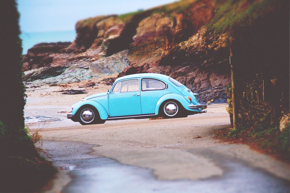 teal Volkswagen Beetle on seashore