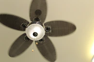 A modern ceiling fan spinning gently in a bright, airy room.
