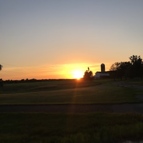 A serene landscape of the farm at sunset with white fences and rolling hills.