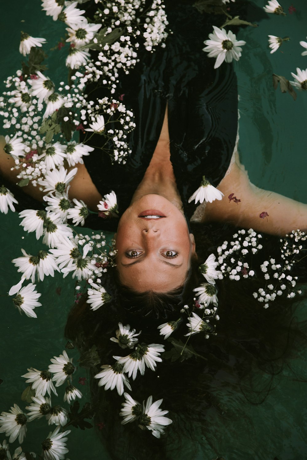 woman swimming covered by white daisies