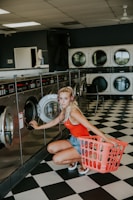 woman kneeling in front of front-load clothes washer inside laundry shop