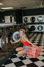 woman kneeling in front of front-load clothes washer inside laundry shop