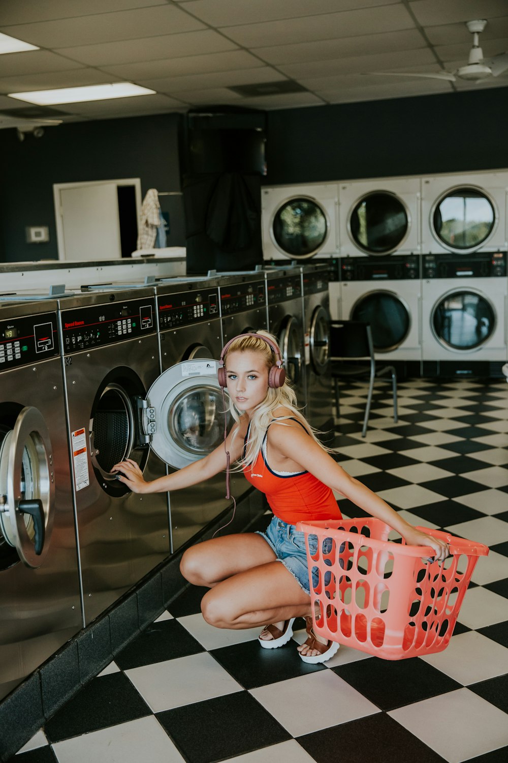 Frau kniet vor Frontlader-Waschmaschine in der Wäscherei