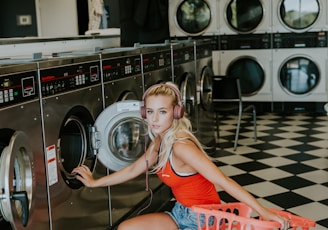 woman kneeling in front of front-load clothes washer inside laundry shop