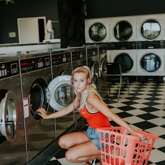 woman kneeling in front of front-load clothes washer inside laundry shop