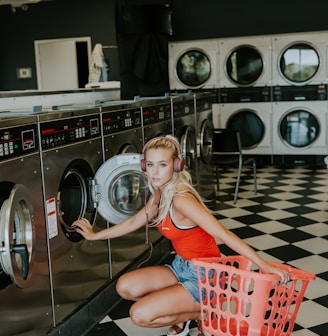 woman kneeling in front of front-load clothes washer inside laundry shop