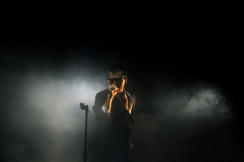 man standing beside microphone stand holding microphone