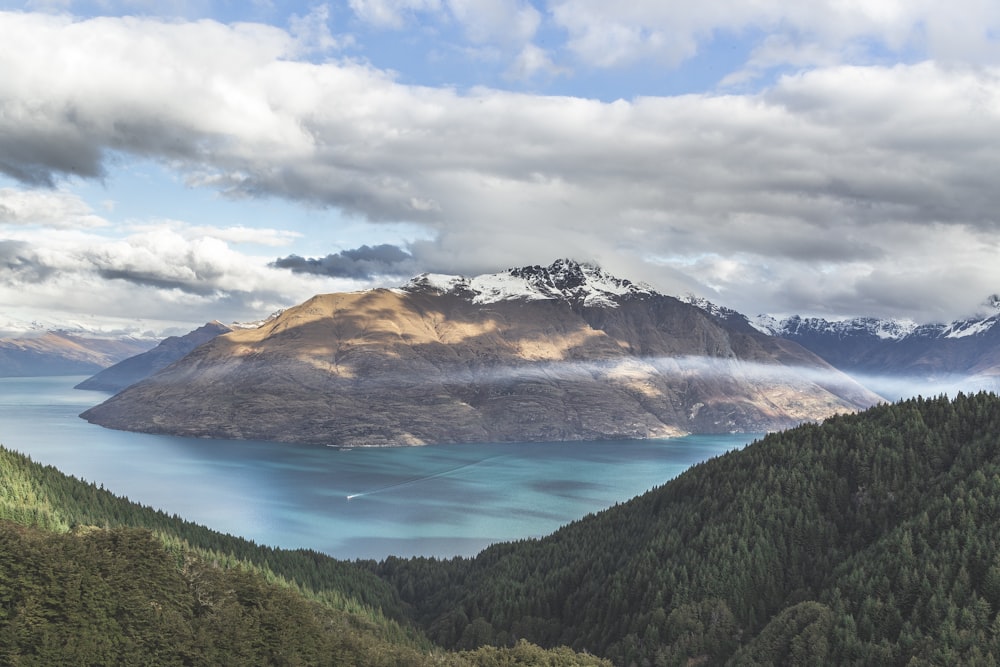 fotografía de paisaje de montaña bajo cielo nublado entre cuerpo de agua durante el día