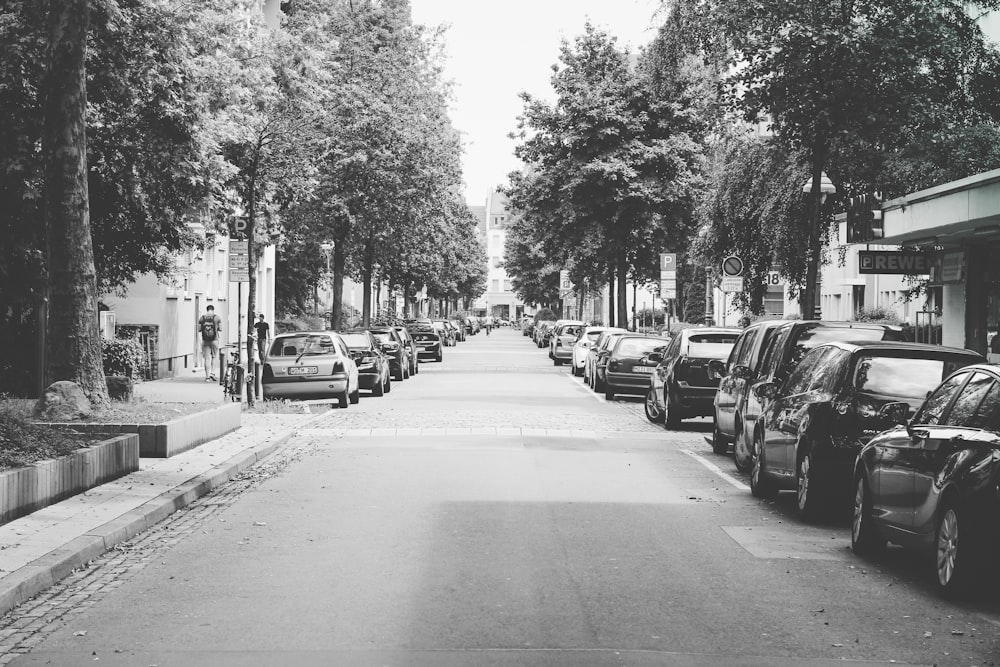 a black and white photo of a street lined with parked cars