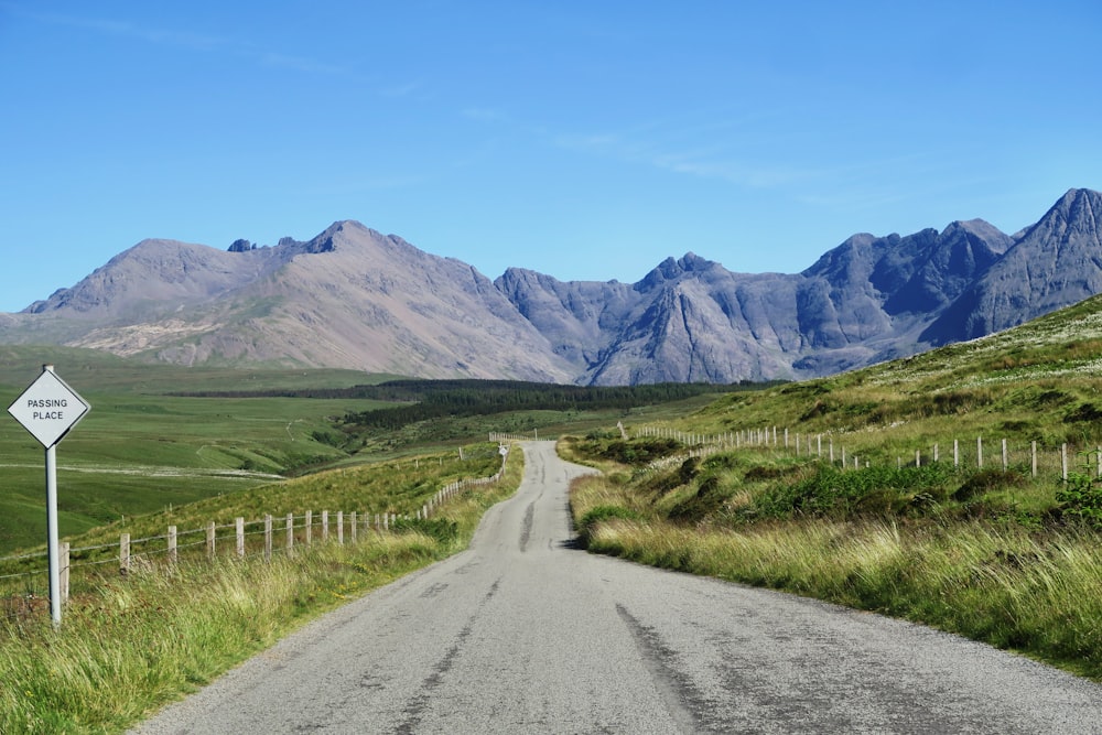 estrada cinzenta com campos verdes longe nas montanhas durante a fotografia diurna