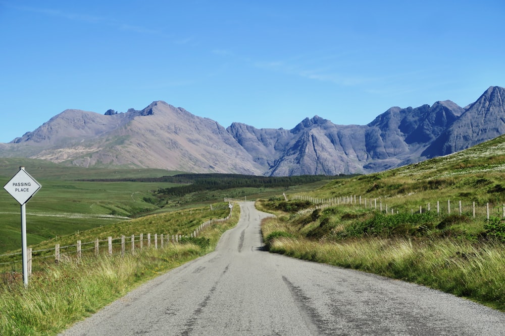 gray road with green fields far at the mountains during daytime photography