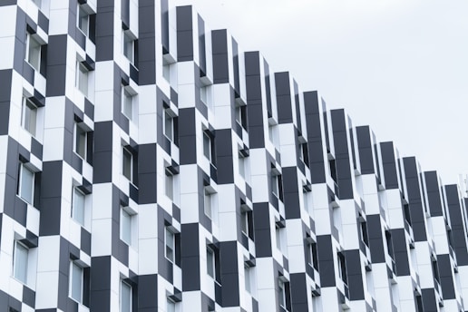 A modern building facade featuring a checkerboard pattern of black and white panels. The symmetrical design includes repetitive windows that add to the geometric aesthetic.