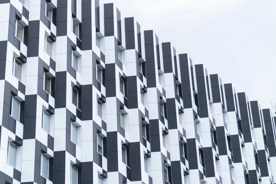 A chequered facade of alternating solid and glazed panels in raking light