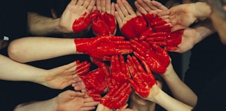 hands formed together with red heart paint