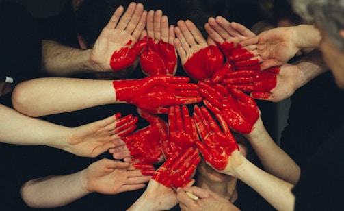 hands formed together with red heart paint