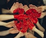 hands formed together with red heart paint