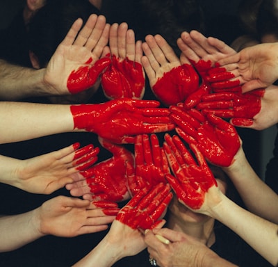 hands formed together with red heart paint