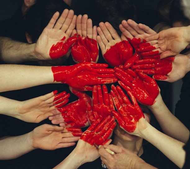 hands formed together with red heart paint