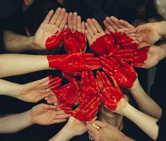 hands formed together with red heart paint