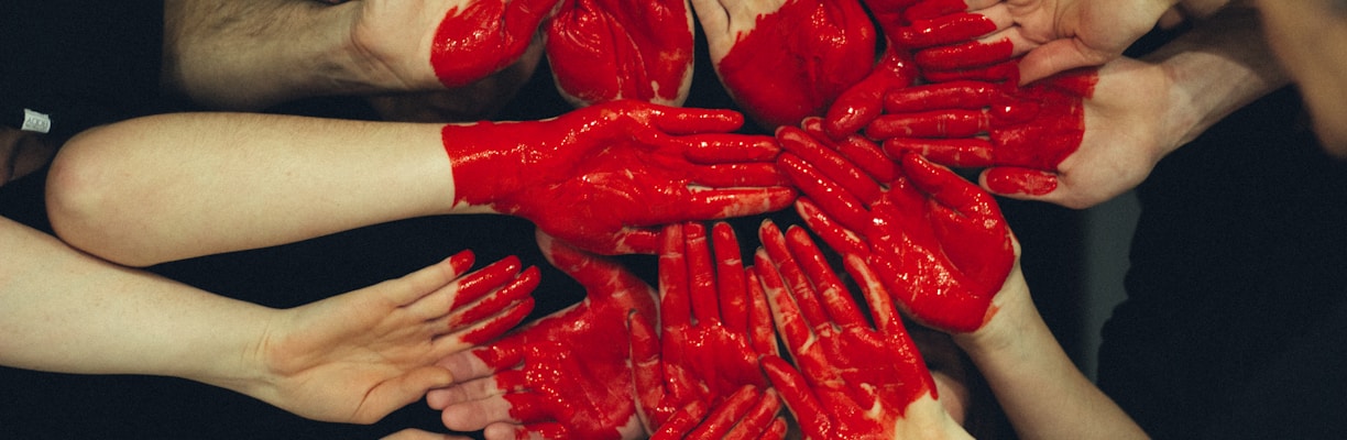 hands formed together with red heart paint