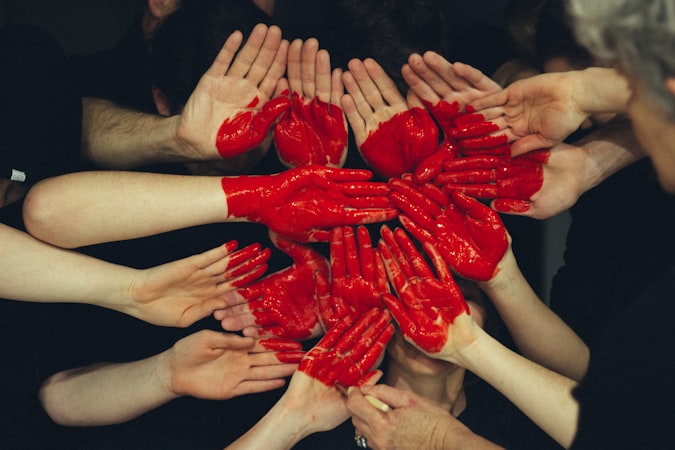 A group of hands with a red heart drawn on them.