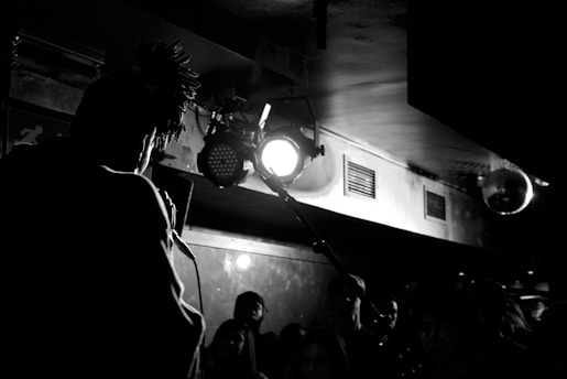 Black-and-white photo of Bruce and Gaynor speaking passionately on stage, spotlight highlighting their connection.