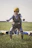 A happy woman with a parachute harness standing on a mountain launch site, ready to fly.