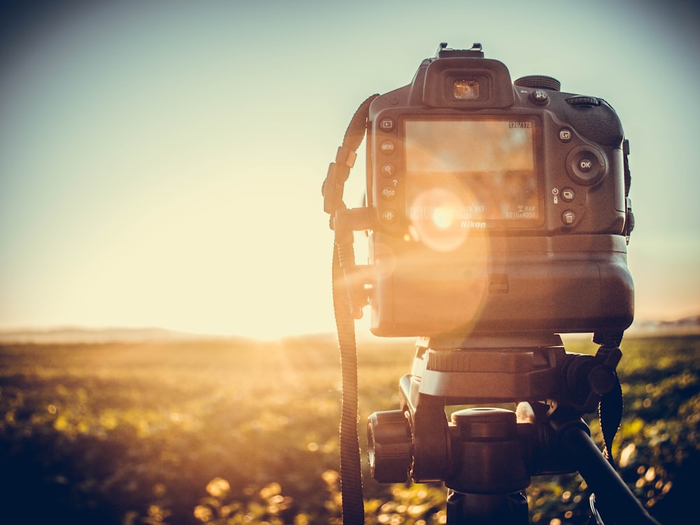 black dslr camera on tripod during sunset