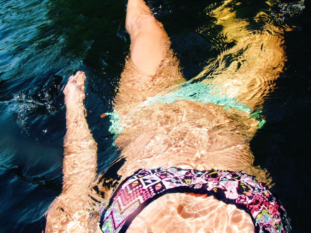mujer en bikini flotando en el cuerpo de agua tranquila