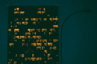 Night view of a modern high-rise residential building illuminated with warm lights against a dark sky.