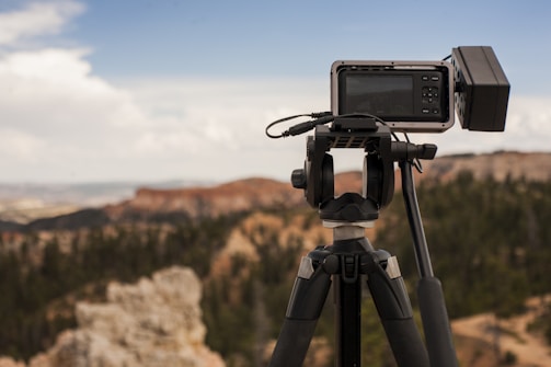 A filmmaker capturing a scenic landscape with a camera on a tripod.