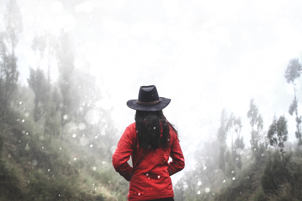Mulher na camisa vermelha em pé perto da floresta