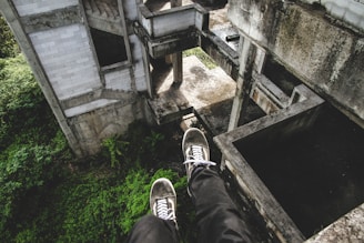person sitting on gray abandoned building